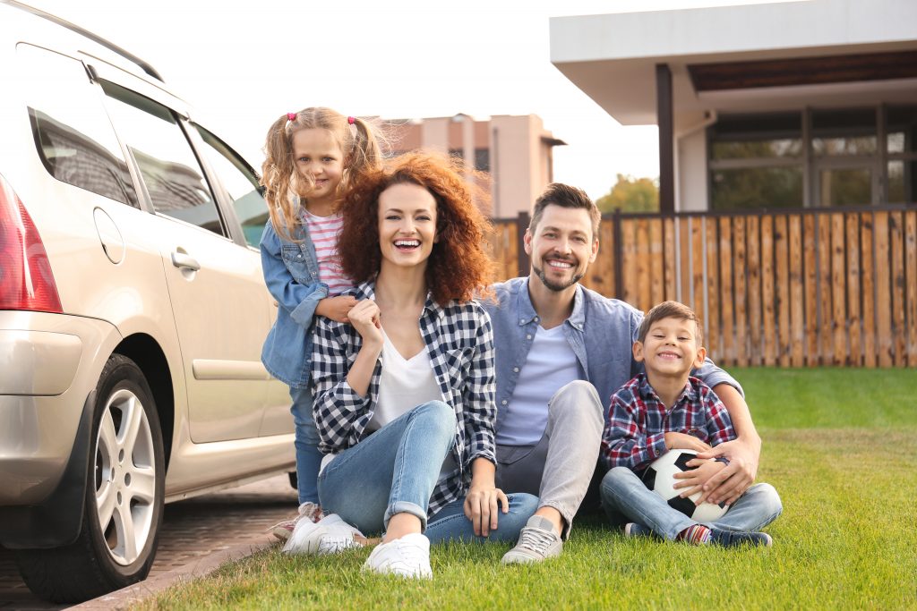 Family smiling by car