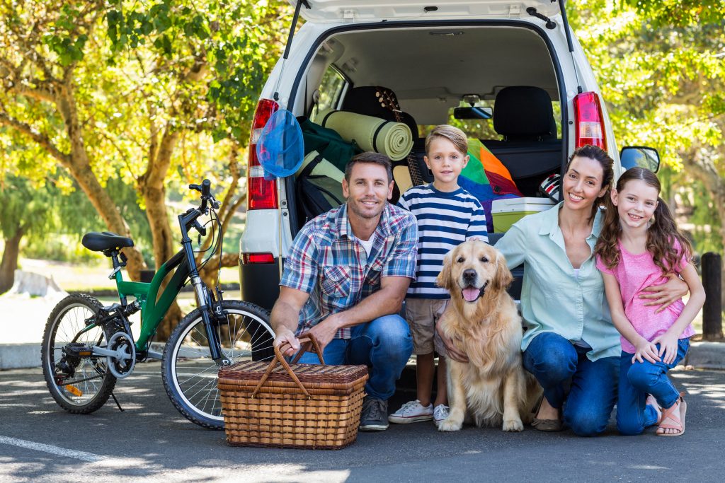 Family and dog going on road trip with picnic basket to save money on food