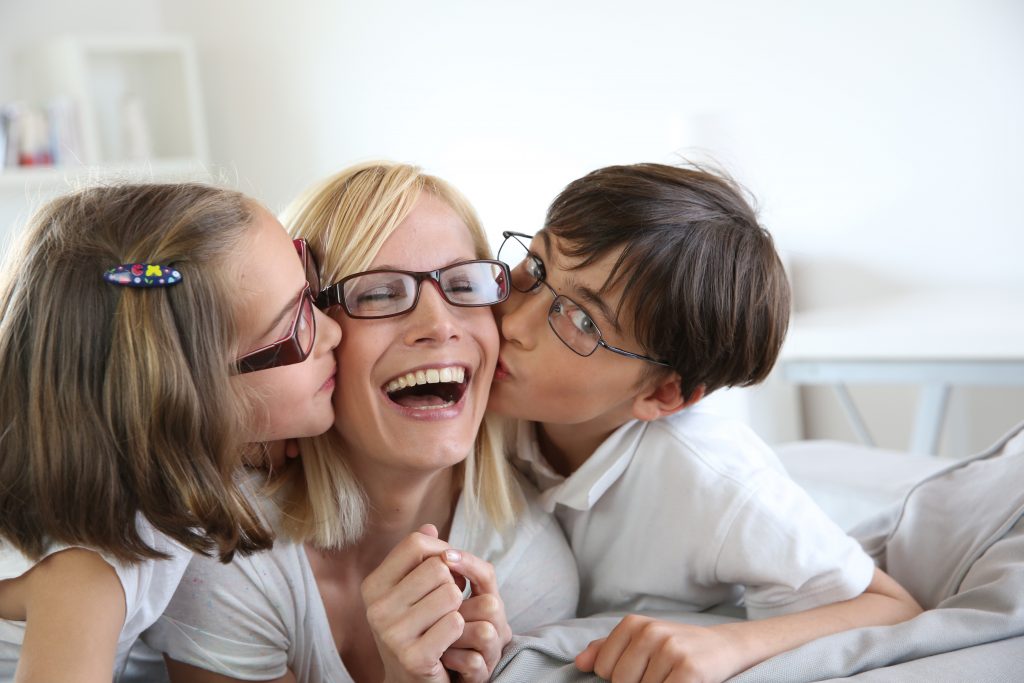 Kids kissing mom. All are wearing glasses.