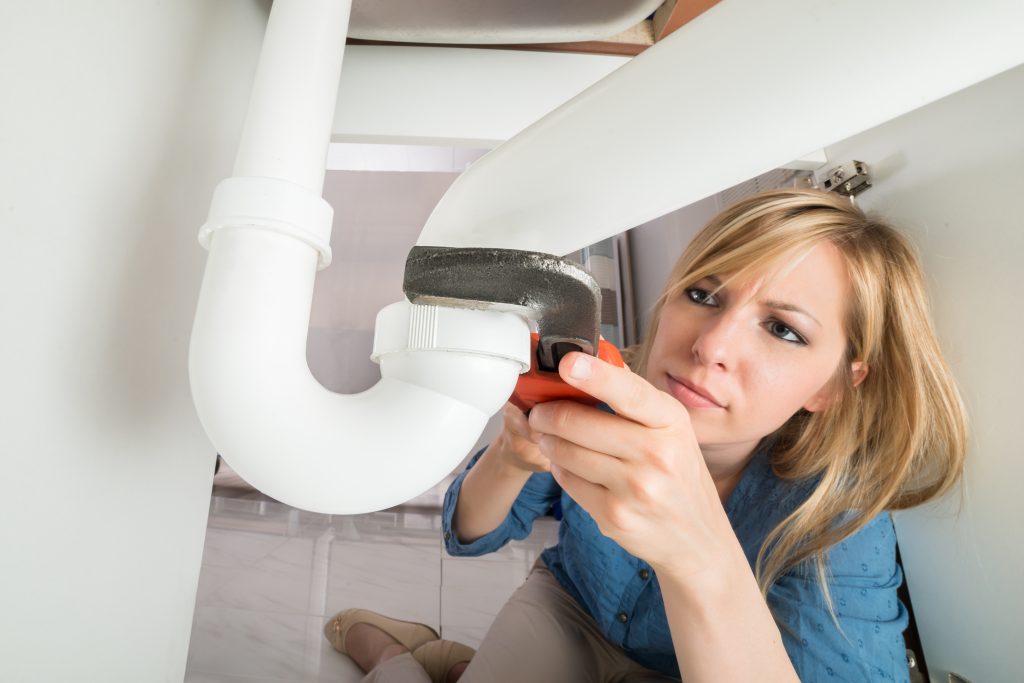 Woman fixing sink to save money