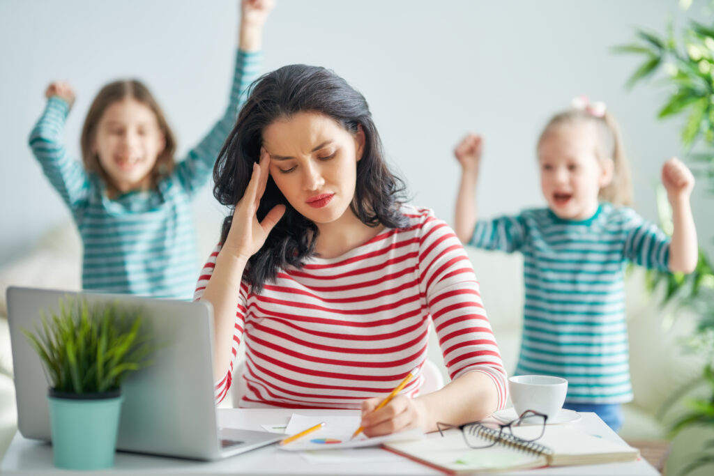 Woman working on computer while girls yell behind her