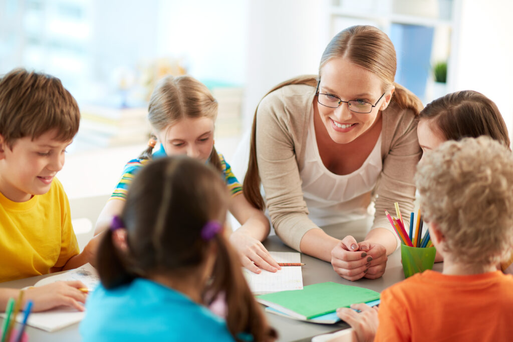 Teacher and students talking at a table during a school lesson