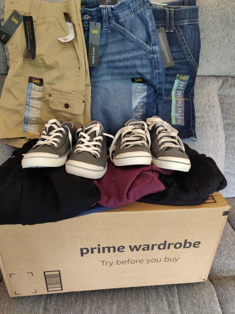 Prime Wardrobe box with clothes and shoes on top of it.