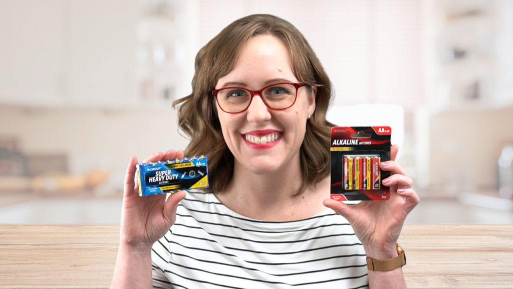 woman holding 2 packs of AA batteries